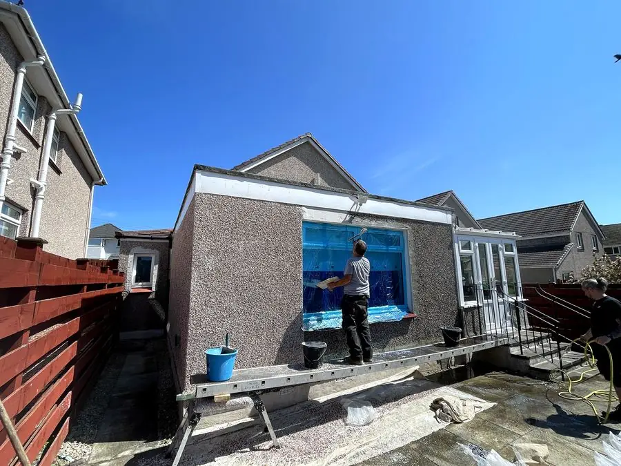 Tradesman applying roughcast to a bungalow extension